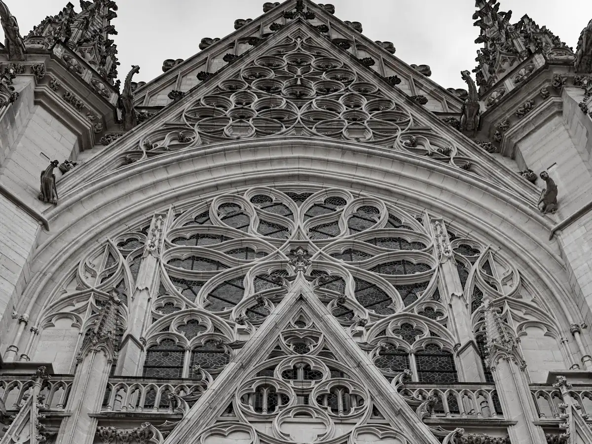 The rose window and stacked carved gables of the Sainte-Chapelle de Vincennes' west front, in black and white